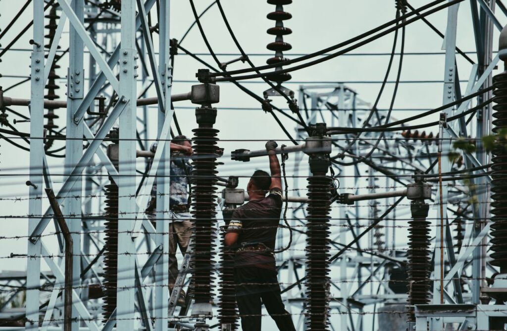 Electricians working on power lines, ensuring grid maintenance and safety.